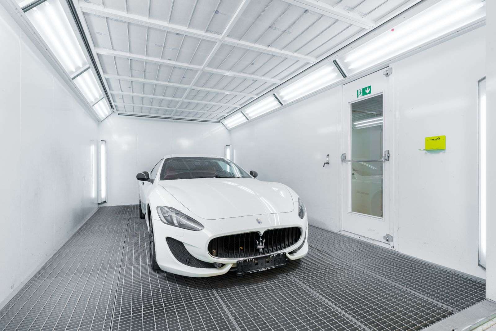 Carro dentro de cabine de pintura automotiva bem iluminada